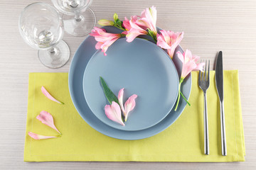 Beautiful festive table setting with floral decor on wooden surface
