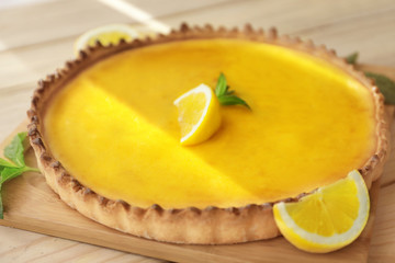 Wooden board with tasty lemon curd pie on table, closeup