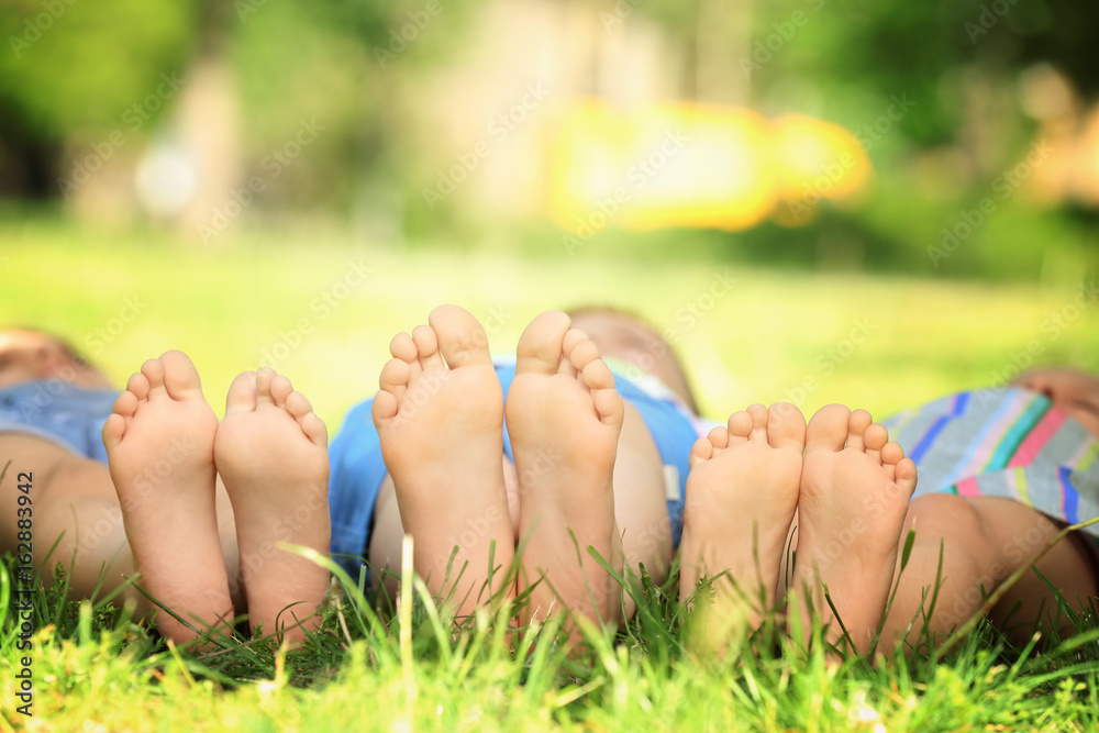 Canvas Prints Feet of cute little children lying on green grass in park