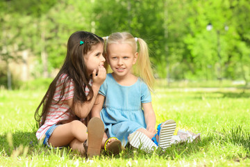 Fototapeta premium Cute little girls sitting on green grass in park