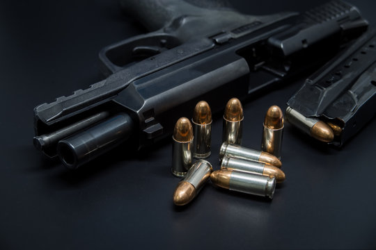 9 mm Pistol, bullets and magazine on drak background. Gun isolated