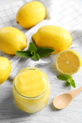 Glass jar with yummy lemon curd on white wooden table