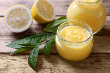 Obraz na płótnie Canvas Glass jars with yummy lemon curd on wooden table