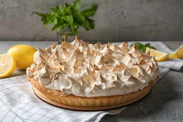 Tasty lemon meringue pie and napkin on grey table, closeup