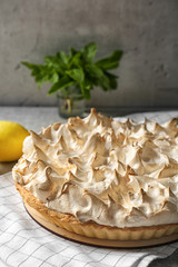 Tasty lemon meringue pie and napkin on kitchen table, closeup