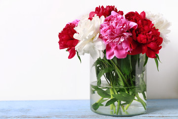 Glass vase with beautiful peonies on wooden table