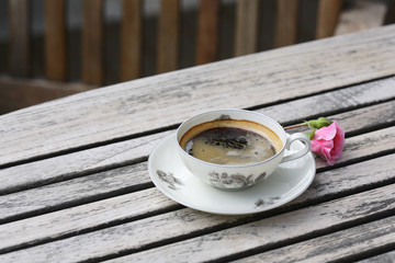 Coffee in a flowered cup on a wooden table on the terrace