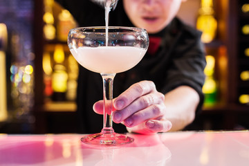 The barman pours a cocktail on the bar