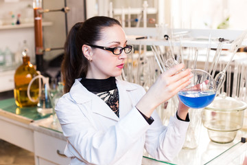 A scientist in a laboratory studying the liquid in the beaker