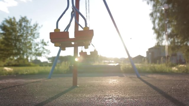 Children swing swaying in a summer park at sunset. no people