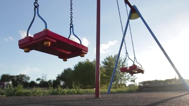 Children swing swaying in a summer park at sunset. no people