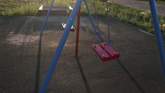 A swing on chains without people lingering alone in an empty park at sunset. Sense of loneliness