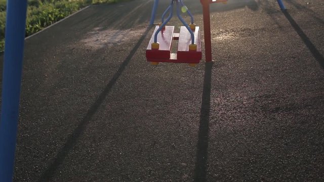 Children swing swaying in a summer park at sunset. no people