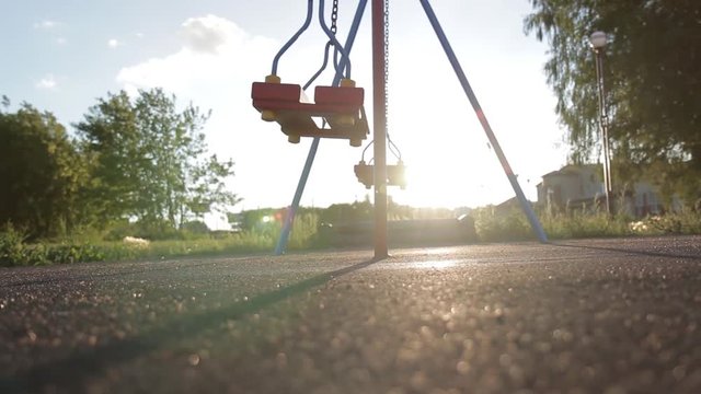 A swing on chains without people lingering alone in an empty park at sunset. Sense of loneliness
