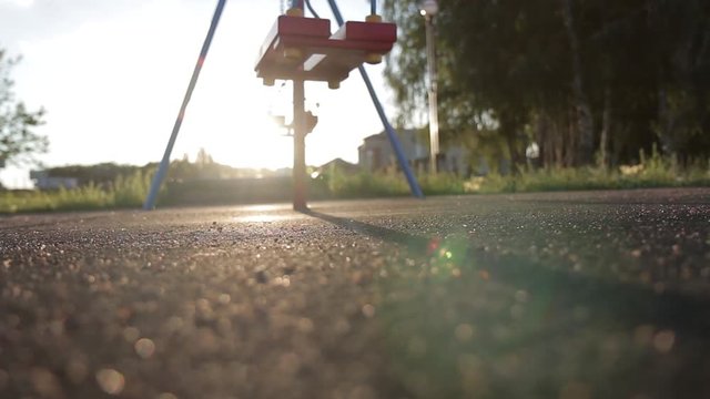 Children swing swaying in a summer park at sunset. no people