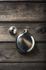 Metall round flask with cup on wooden backdrop