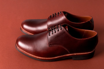 Brown oxford shoes on red background. Close up.