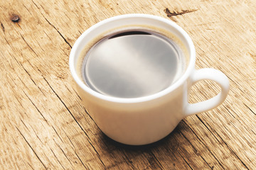 Cup of black coffee on old wooden table - studio shot