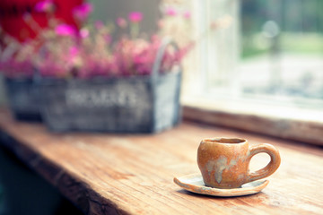 Coffee cup in coffee shop with flower pot on background