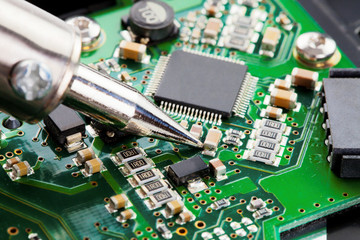 Close up studio shot of soldering iron and microcircuit