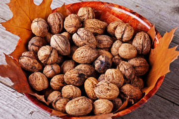 Walnuts amidst autumn leaves on a wooden table