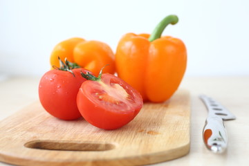 orange bell pepper, tomato and knife on Board