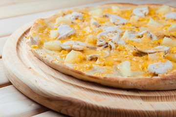Pizza with pineapple on the wooden background