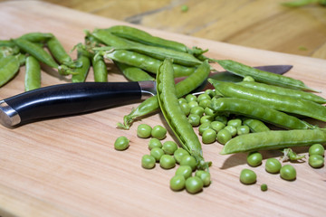 Pea and knife on a wooden board
