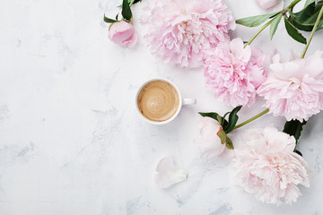 Morning coffee and beautiful pink peony flowers on white stone table top view in flat lay style....