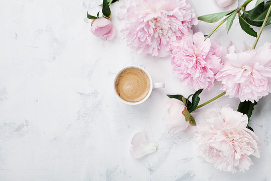 Morning coffee and beautiful pink peony flowers on white stone table top view in flat lay style. Cozy breakfast on Mother or Woman day.