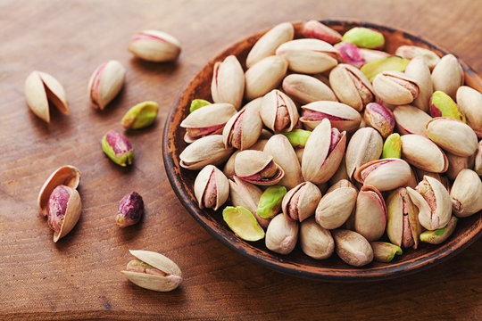 Bowl of pistachio nuts on wooden rustic table. Healthy food and snack.