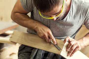 man treating a wooden product with a chisel