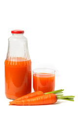 A glass bottle and a glass of carrot juice with whole carrots.
