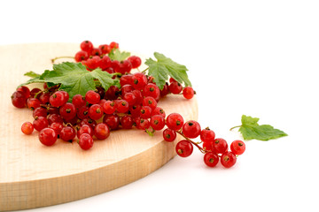 Ripe red currants on a wooden plate