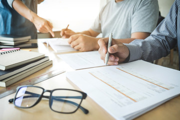Education, teaching, learning and people concept. Group of high school students or classmates with helps friend catching up workbook learning in classroom, Tutor books with friends
