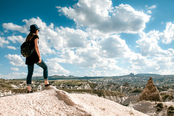 Young beautiful travel girl with a backpack on top of a hill in Cappadocia, Turkey. Travel, success, freedom, achievement.