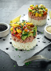 Tuna sushi stacks with mango, cucumber, tomatoes salsa served with balsamic vinegar, nigela ans sesame seeds