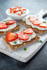 Homemade Crispbread toast with Cottage Cheese and Strawberry on white wooden board.