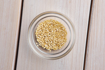 Top view of sesame seeds in a little bowl on wooden table.