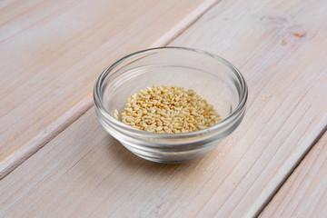 Sesame seeds in a little glass bowl on wooden table.