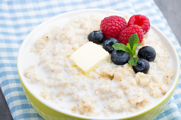 Oatmeal porridge in bowl with berries raspberries and blackberries.