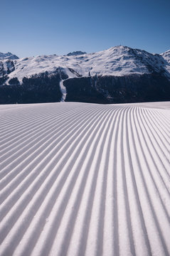 A closeup perspective of a perfectly groomed ski run with Alps in the background, Livigno, Italy