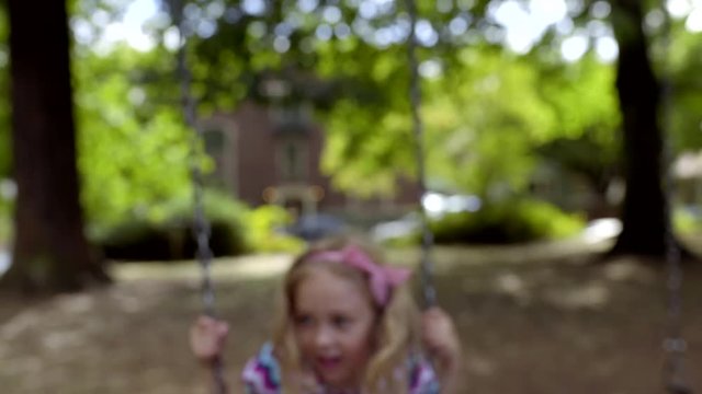 Little Girl Enjoys Swinging On Swing Set In Park (Slow Motion)