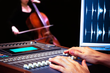 sound engineer hands working on digital sound mixer for cello recording
