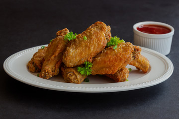 Fried chicken wings on white plate served with barbecue dipping sauce. Homemade fried chicken...