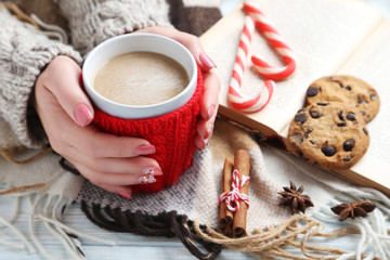 Woman hands holding cup of coffee on wooden table