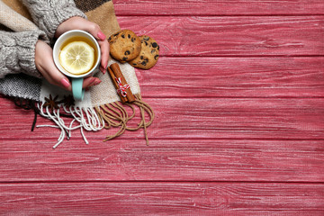 Woman hands holding cup of tea on wooden table