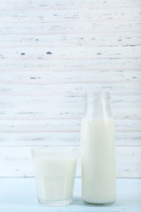 Glass and bottle of milk on wooden table