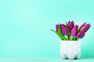 Bouquet of tulips in cup on green background