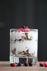 Granola and yogurt with berry in a drinking glass on table close-up side view studio photo  